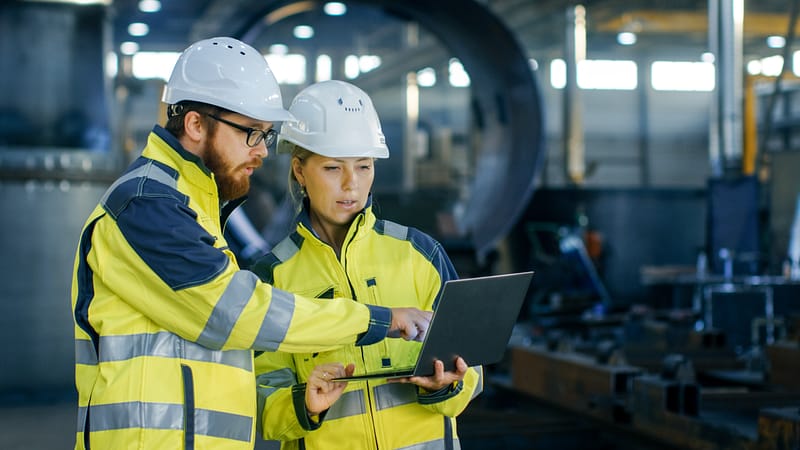 Male and Female Industrial Engineers in Hard Hats Discuss New Pr